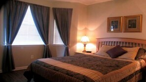A hotel room with a bed, curtains, a lamp, and two framed pictures on the wall. - Tr603 - Terrace Ridge - 2 Bed 2 Baths Condo (Davenport)