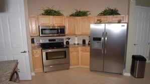 A kitchen with wooden cabinets, a stainless steel refrigerator, a microwave, an oven, and a sink. - Tr421 - Terrace Ridge - 2 Bed 2 Baths Condo (Davenport)