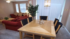 Ein Essbereich mit einem Holztisch und Stühlen, einem roten Sofa und einem Blumentopf.
