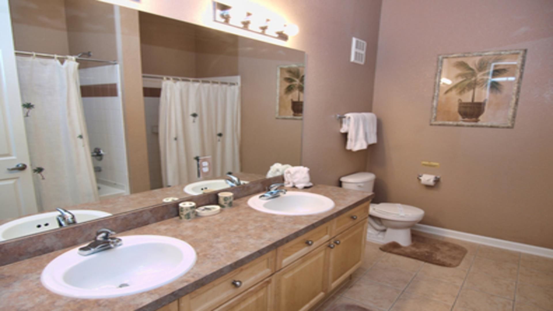 A bathroom with two sinks, a toilet, and a shower.