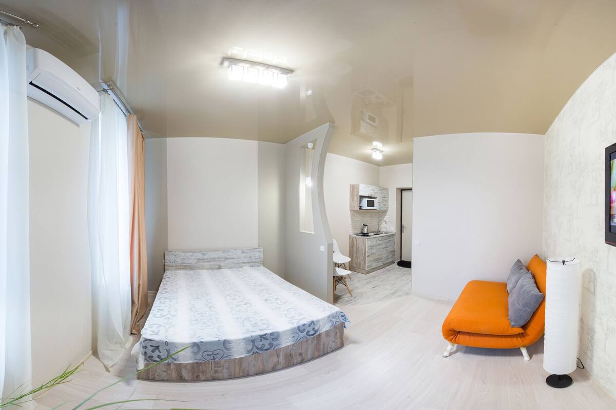 Una habitación pequeña con cama, kitchenette y zona de estar.