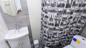 Un baño con lavamanos, inodoro y cortina de ducha con estampado de paisaje urbano.