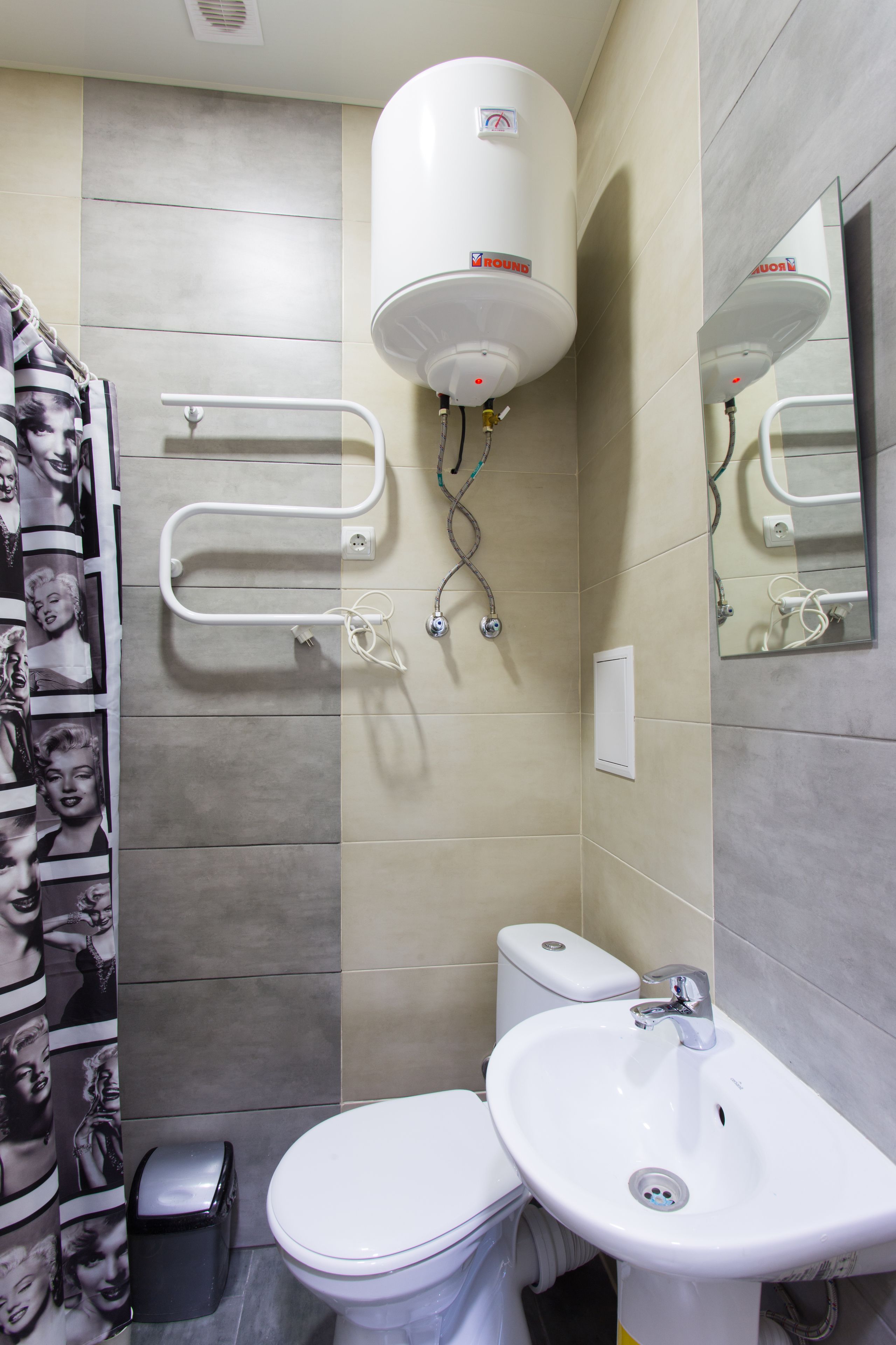Une salle de bain équipée de toilettes, d’un lavabo et d’un chauffe-eau fixé au mur.