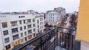 A cityscape with multi-story buildings, a busy street, and a balcony with a railing.