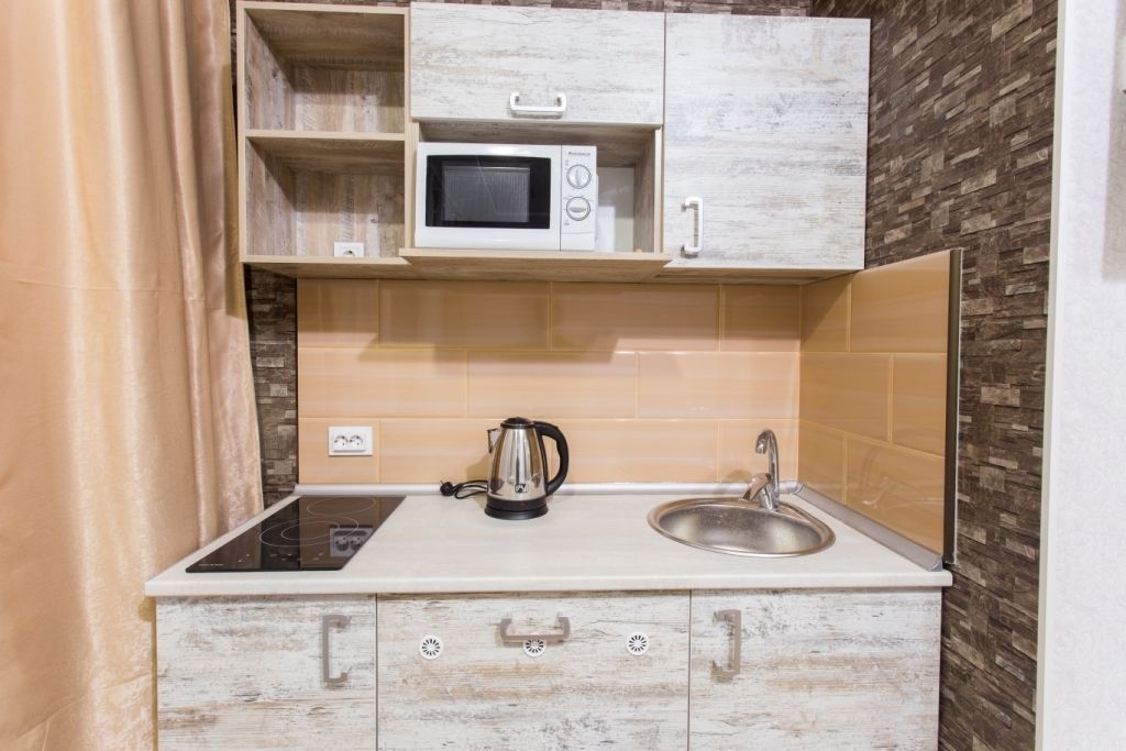 Cozinha compacta com micro-ondas, chaleira e pia.