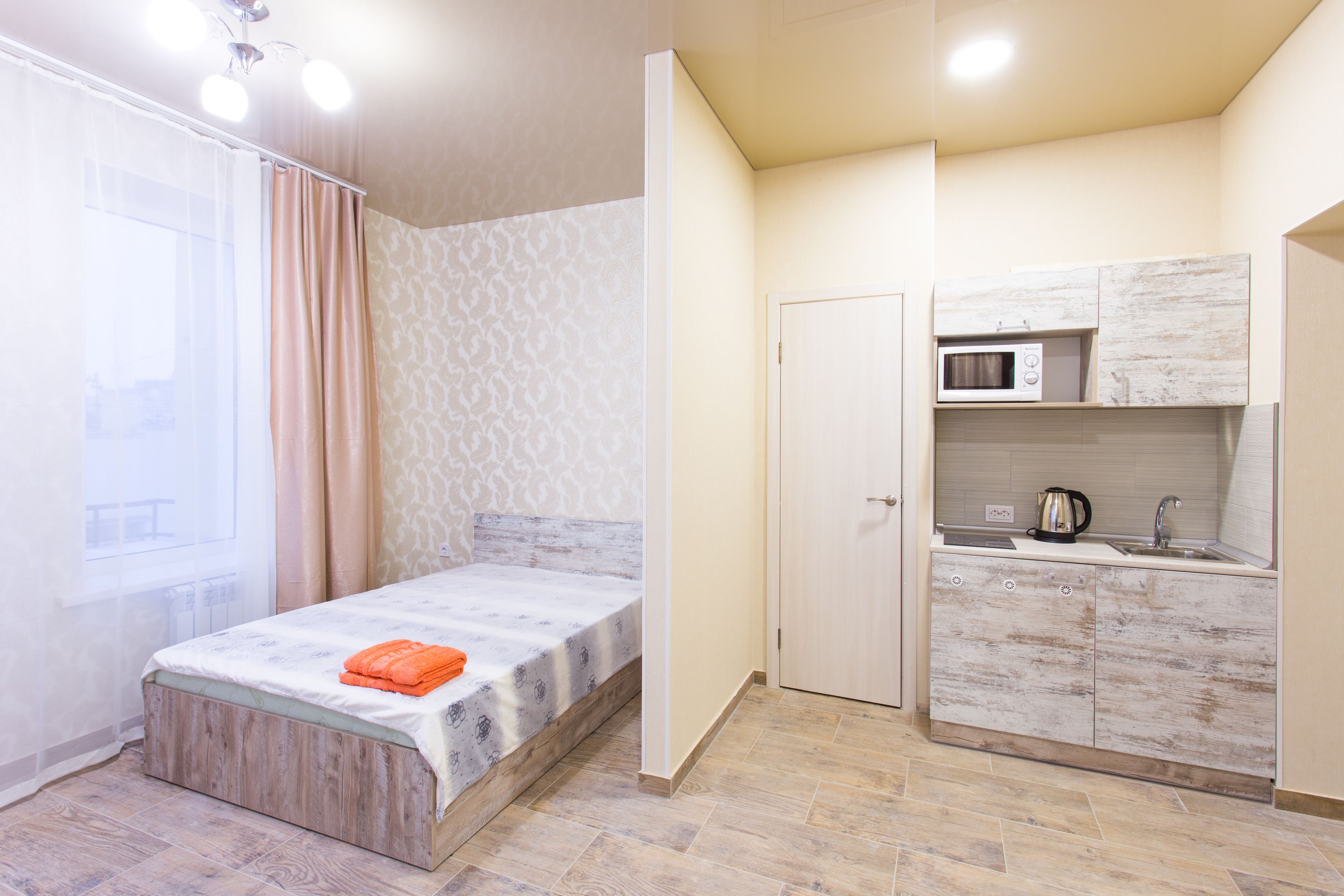 Une petite chambre comprenant un lit, une kitchenette et une salle de bain.