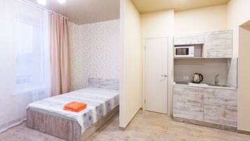 Ein kleines Zimmer mit Bett, einer Küchenzeile und einem Badezimmer.