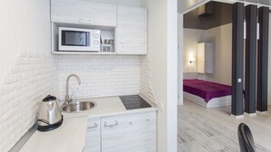 A compact kitchenette with a microwave, kettle, and sink.