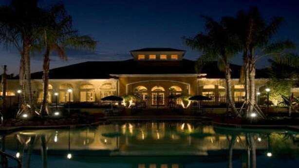 A hotel with a pool, palm trees, and a well-lit facade at night. - Ws305 - Watersong - 5 Bed 5 Baths Villa (Davenport)