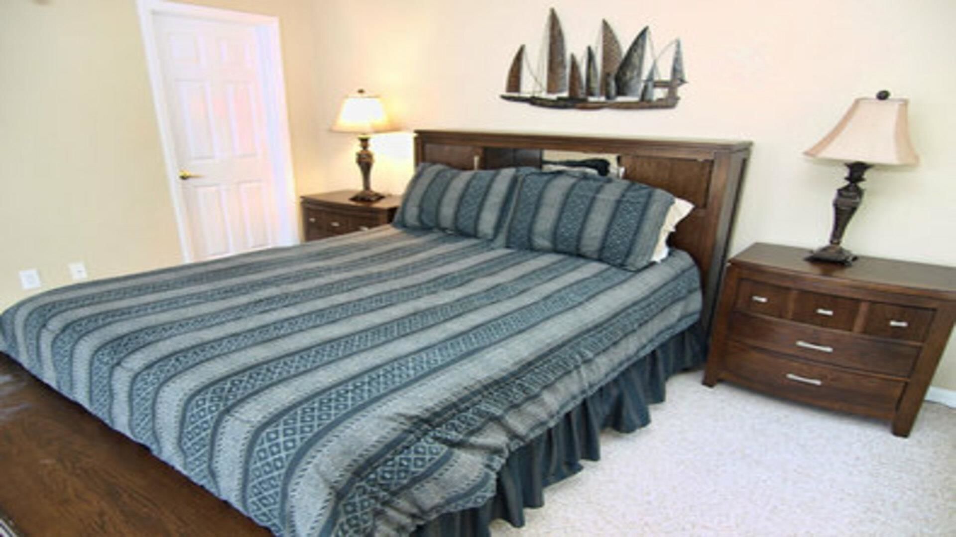 Un dormitorio con una cama, dos mesitas de noche, un aparador y un adorno náutico en la pared.