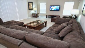 A living room with a sectional sofa, a coffee table, a TV, and a lamp. - Ws305 - Watersong - 5 Bed 5 Baths Villa (Davenport)