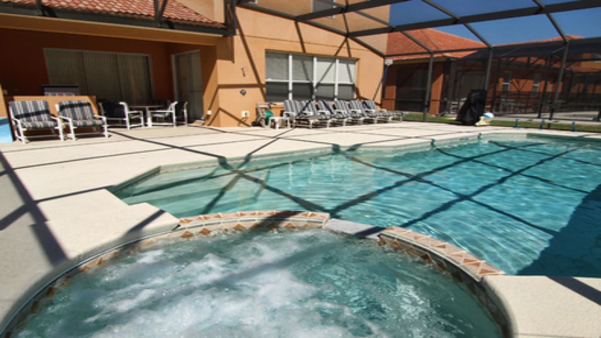 A swimming pool with lounge chairs and a hot tub area.