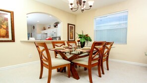 A dining area with a glass-top table, wooden chairs, and a chandelier. - Wh2608 - Windsor Hills Resort - 6 Bed 4 Baths Villa (Kissimmee)