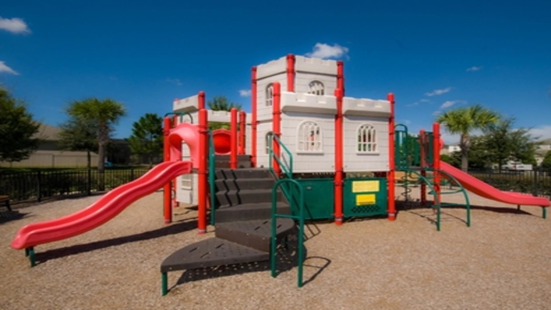 Une aire de jeux avec des toboggans rouges et une structure d’escalade.