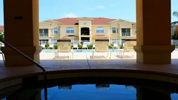 A pool area with lounge chairs and a building with multiple windows and balconies in the background. - Tr319 - Terrace Ridge - 2 Bed 2 Baths Condo (Davenport)