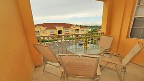 A balcony with a glass table and chairs, overlooking a residential area with houses and a clear sky. - Tr319 - Terrace Ridge - 2 Bed 2 Baths Condo (Davenport)