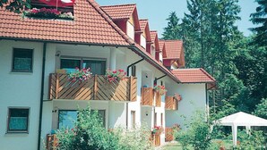A multi-story building with a red-tiled roof, balconies with wooden railings, and flower boxes.
