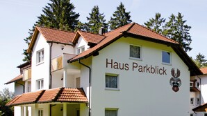 A multi-story building with a sign reading "Haus Parkblick" and a coat of arms.