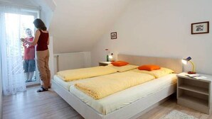 A bedroom with two beds, a nightstand, a bedside lamp, and a window with curtains.
