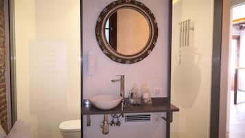 Un baño con un espejo redondo, un lavabo y artículos de aseo.