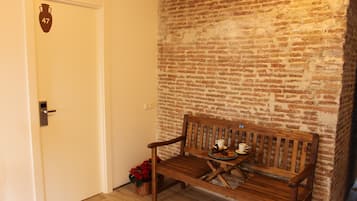 A wooden bench against a brick wall with a door labeled '47' and a basket with flowers.