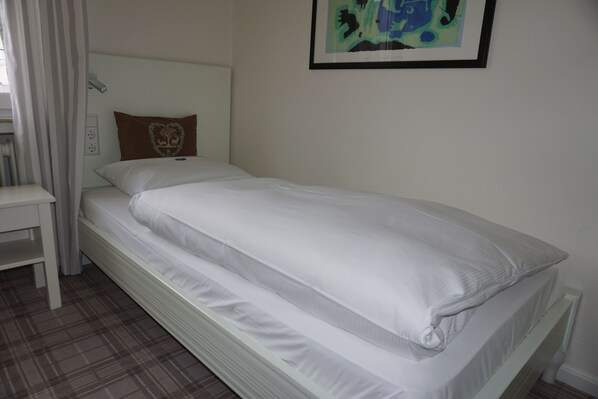 A single bed with white bedding, a headboard, and a brown pillow with a heart design. - Landgasthof Läuterhäusle (Aalen)