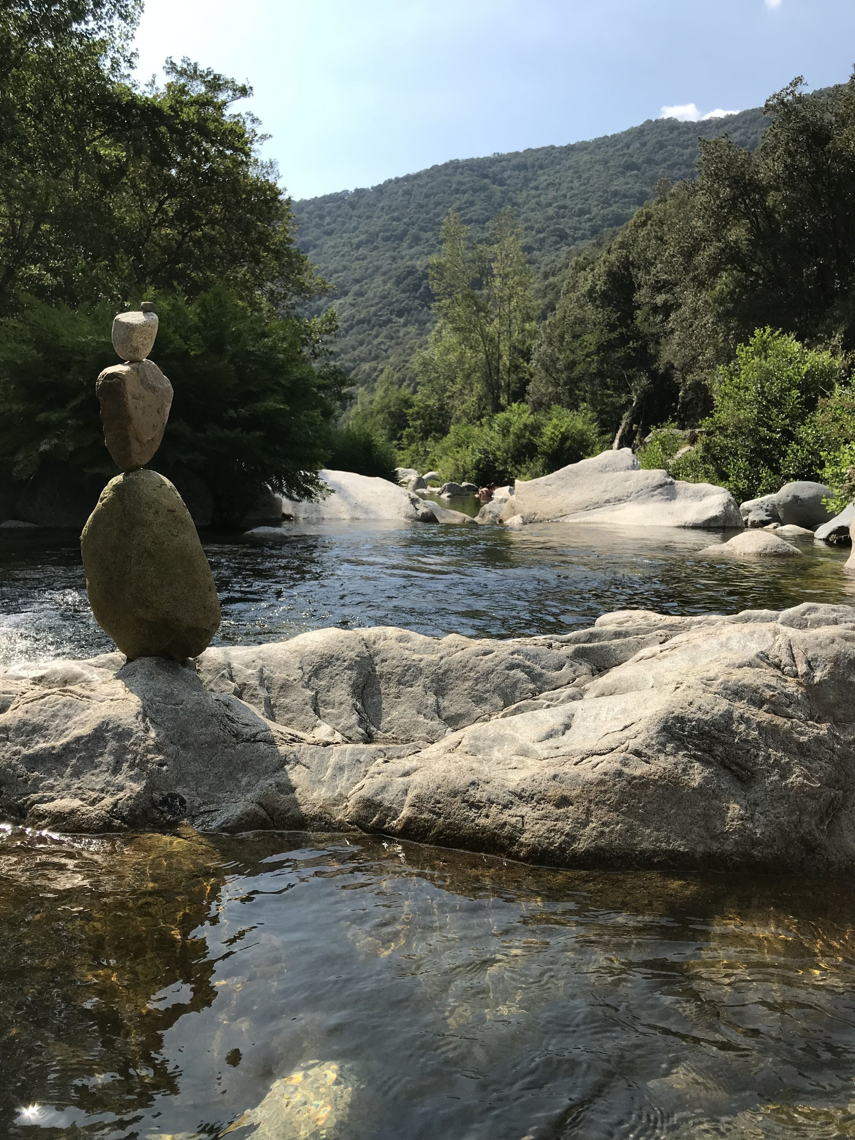 A natural landscape with a river, rocks, and trees.