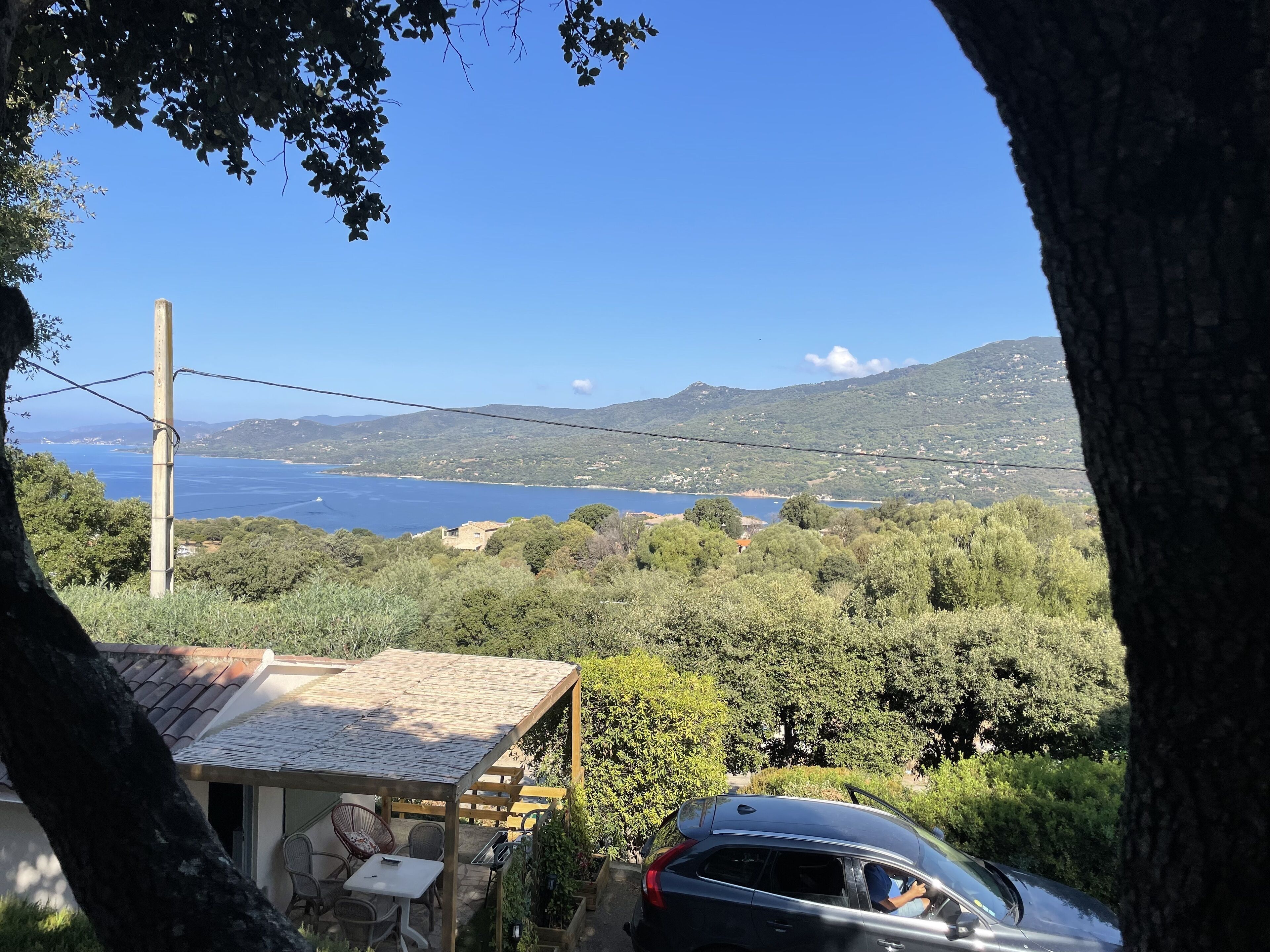 Vista de una zona costera con una casa, un coche y un cielo despejado.