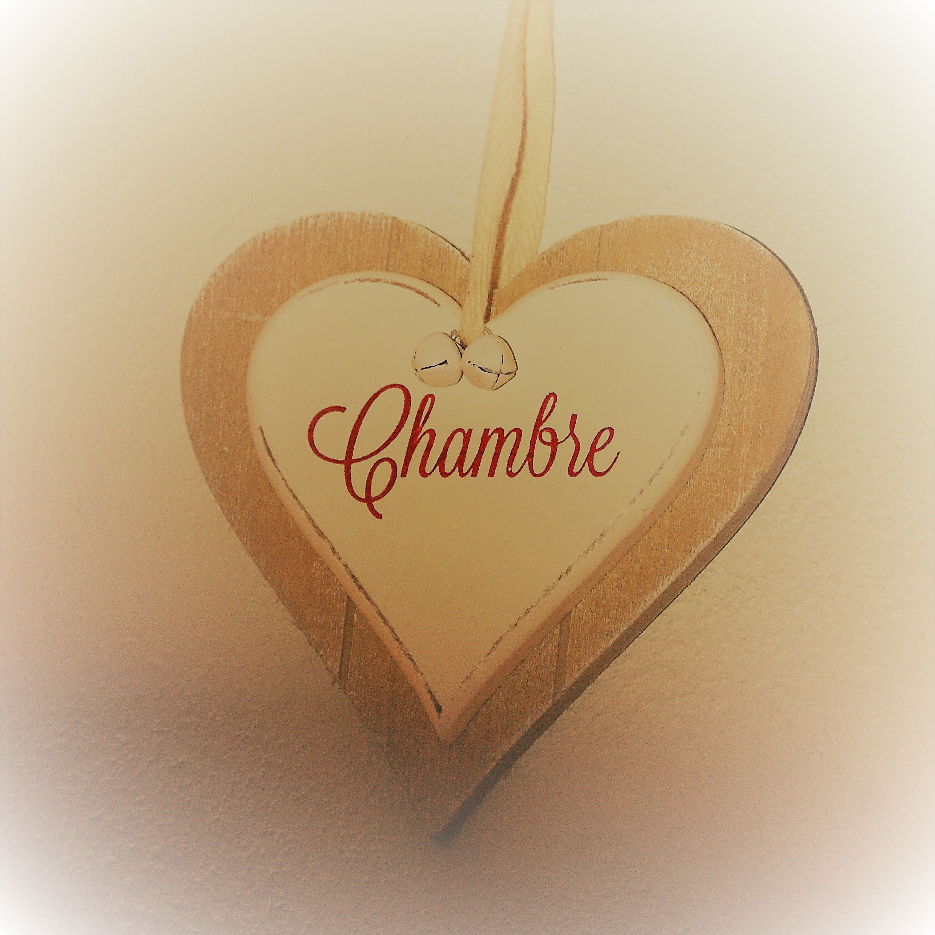 Een houten hartvormige versiering met daarop de tekst 'Chambre'.