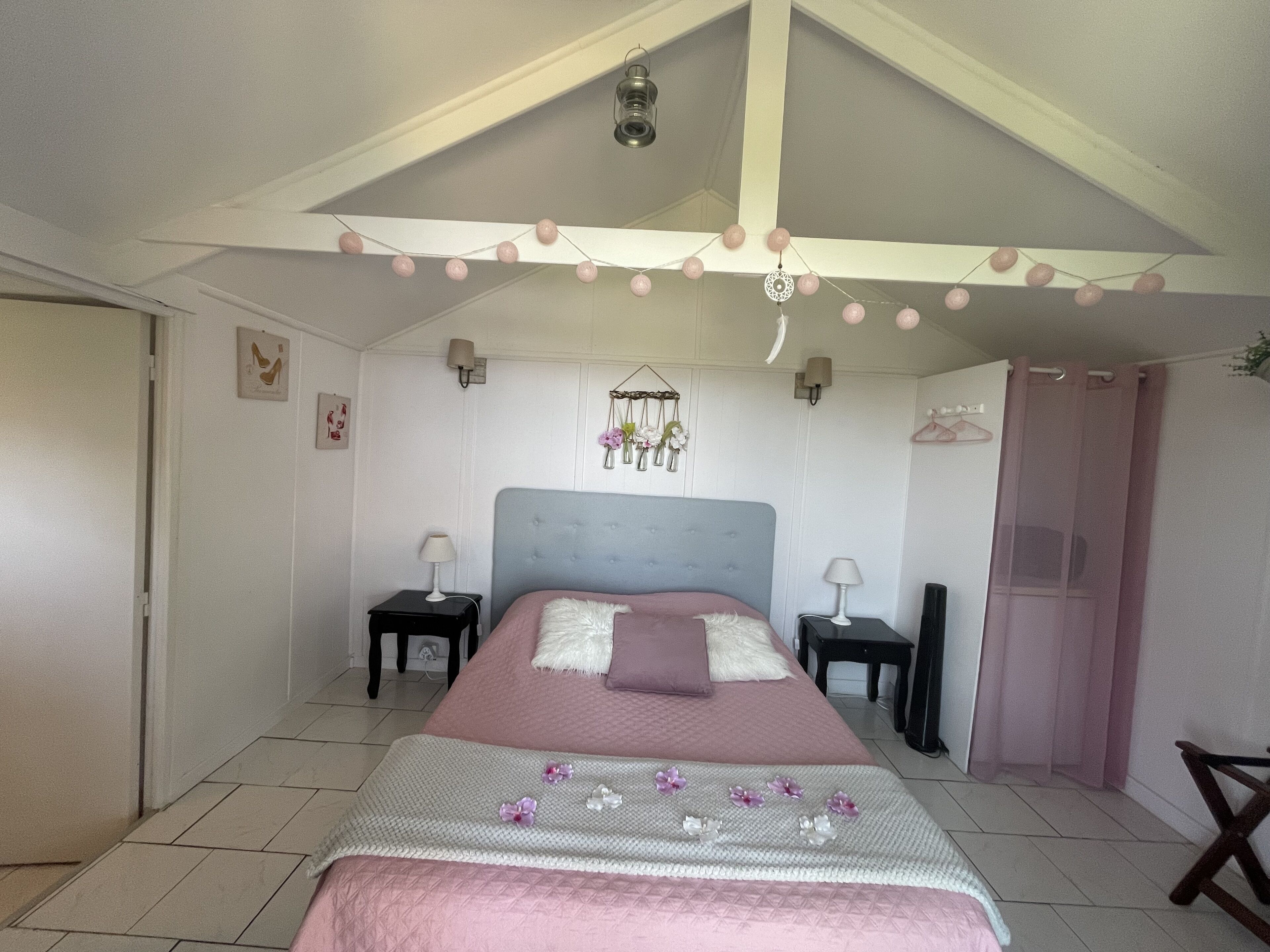 Un dormitorio con cama, dos mesitas de noche, una lámpara colgante y un armario.