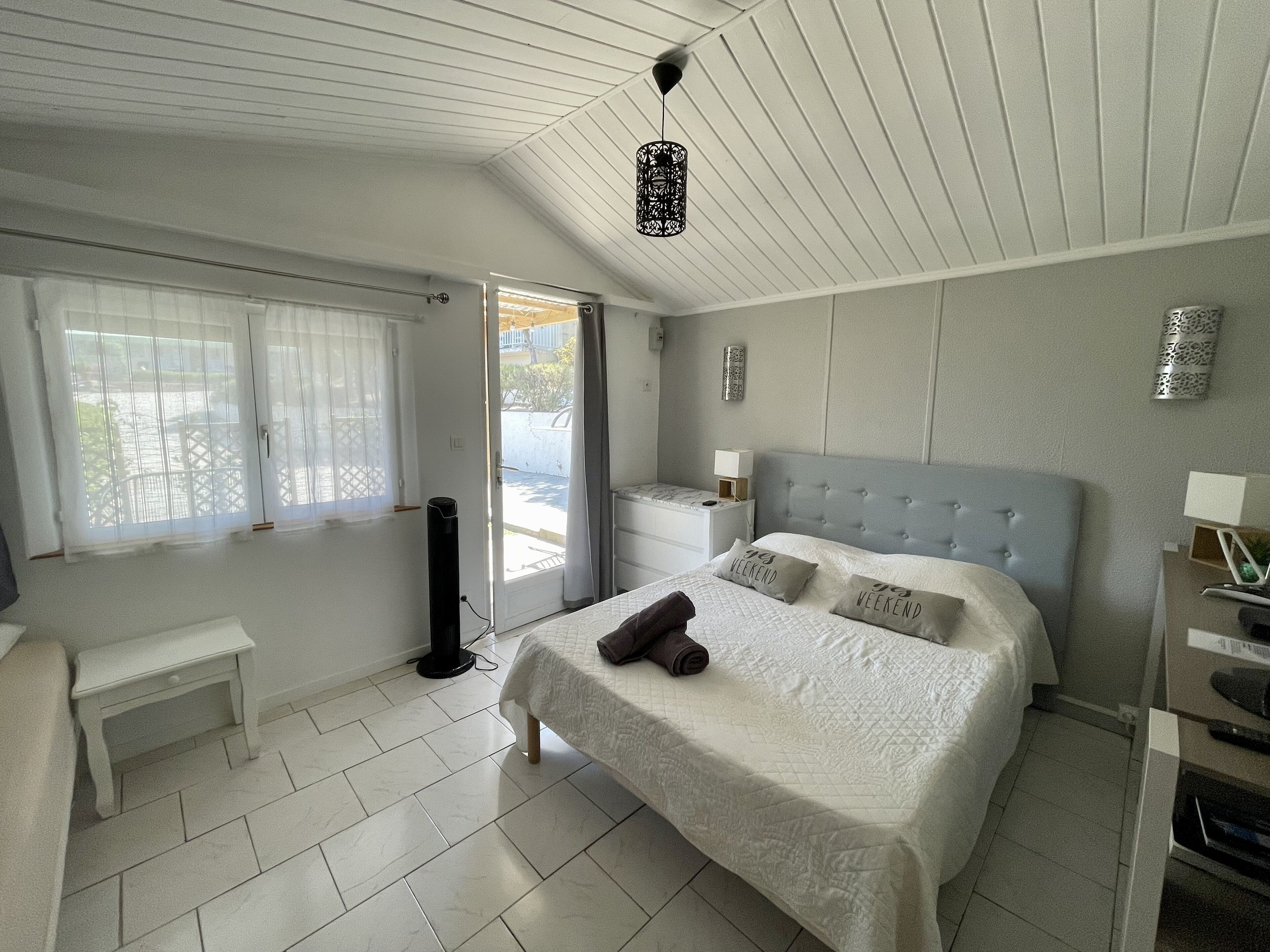 A bedroom with a bed, bedside tables, a desk, and a window with curtains.