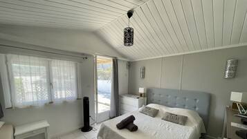 A bedroom with a bed, bedside tables, a desk, and a window with curtains.