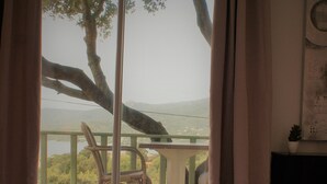 Een slaapkamer met uitzicht op een balkon, een rieten stoel en een kleine tafel.