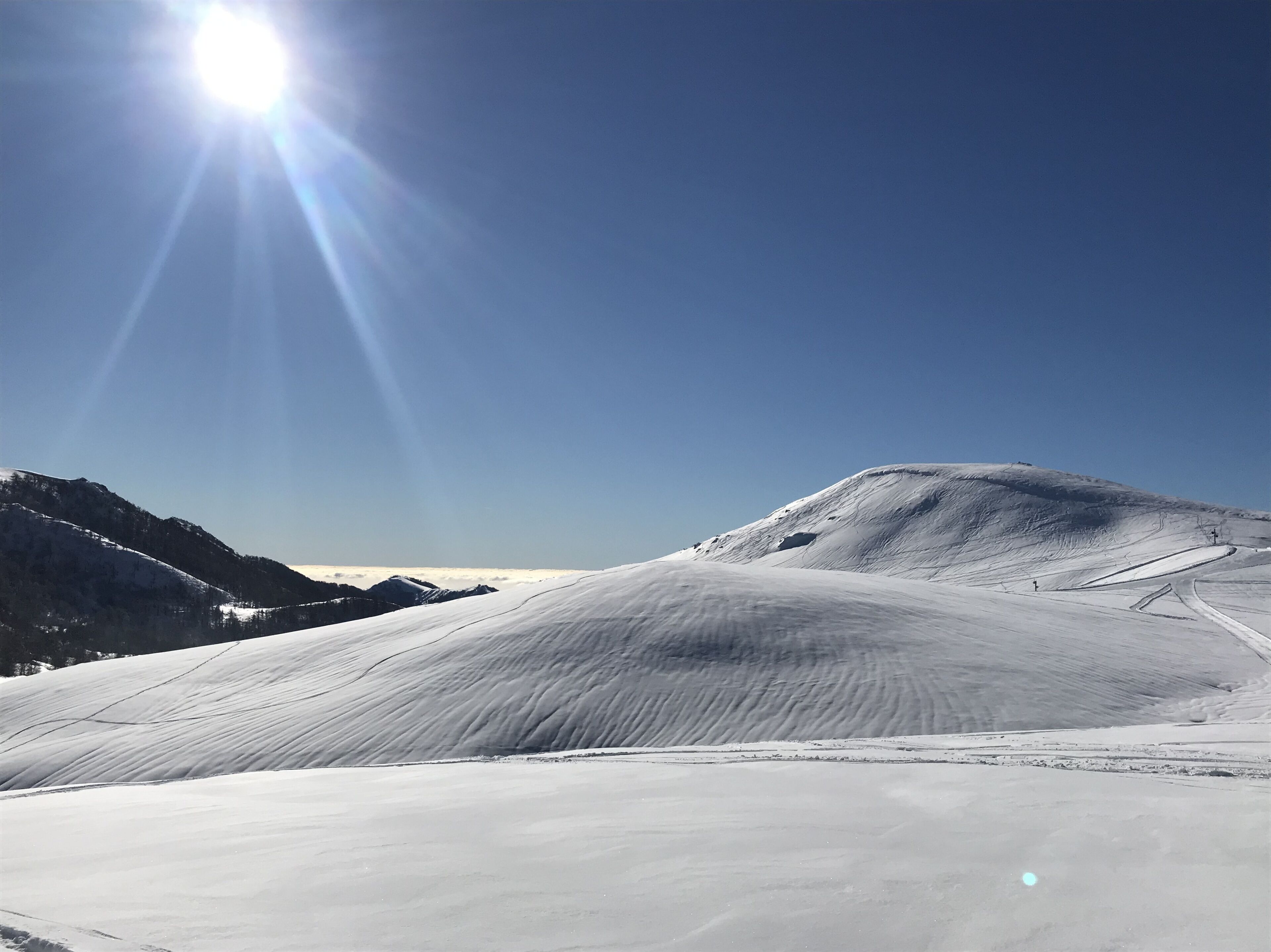 A snow-covered mountain landscape with a clear sky and sunlight.