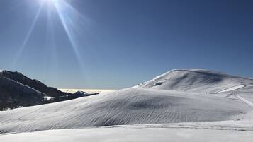 A snow-covered mountain landscape with a clear sky and sunlight.
