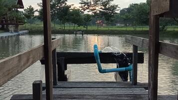 A wooden dock extending over calm water with a blue pipe.