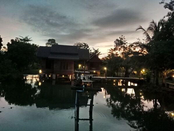A traditional wooden building with a reflection in the water, surrounded by trees and a dock. - Home Style Resort (Chamni)
