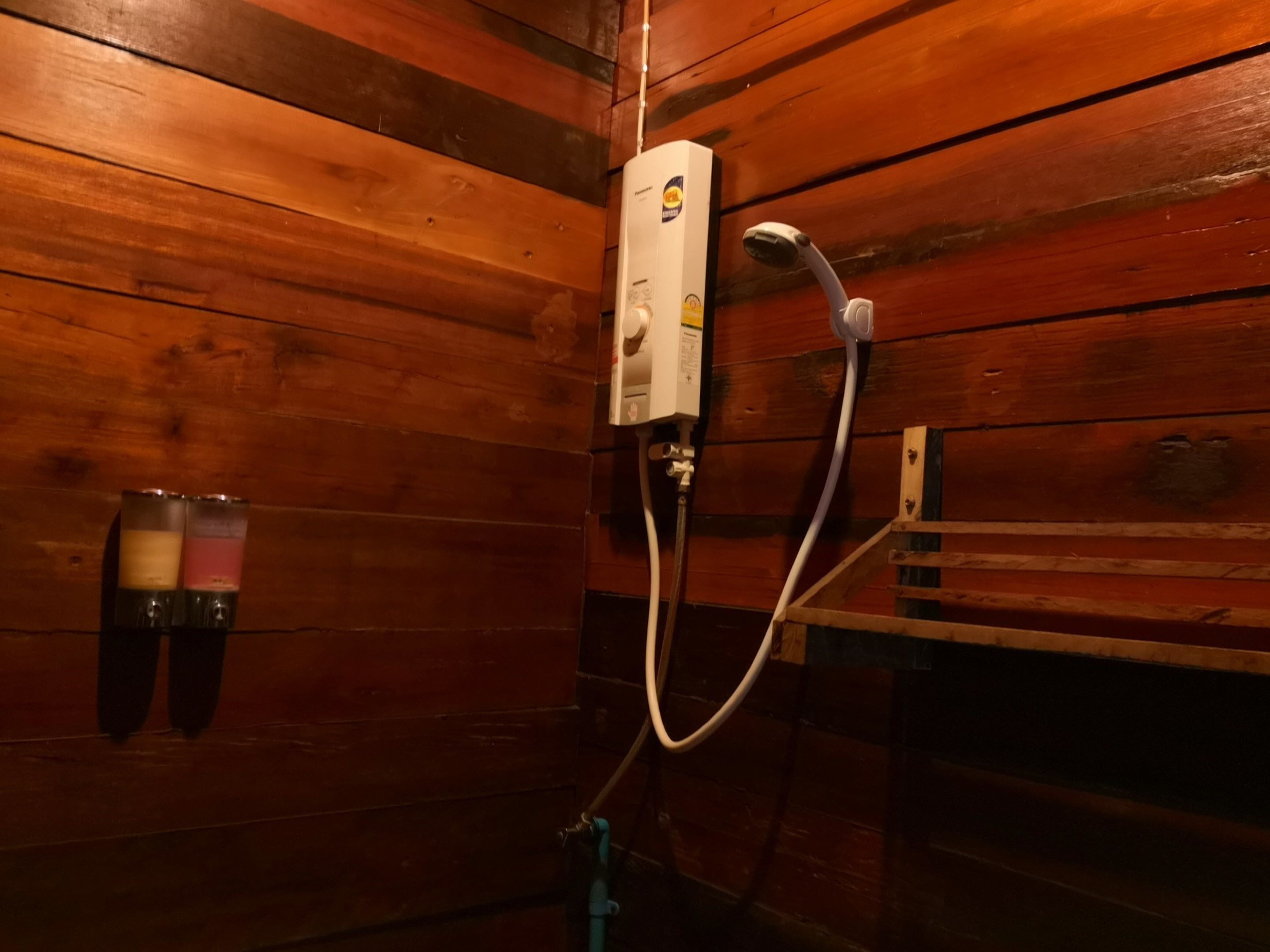 Interior de una cabaña de madera con ducha integrada y calentador de agua.