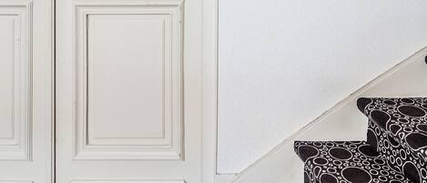 A white door with a handle, a wall-mounted decorative item, and a staircase with patterned steps.