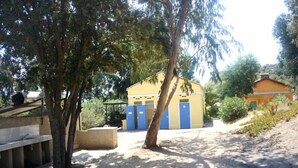 A building with blue doors, surrounded by trees and a dirt path. - Monte Ortu (Lumio)