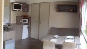 A compact kitchen with a microwave, a small refrigerator, and a sink. There is a dining table with chairs and a bench. - Monte Ortu (Lumio)