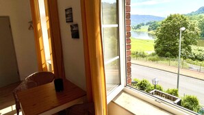 A room with a view of a river, a table, and a chair. - Hotel Klostermühle (Hann. Muenden)