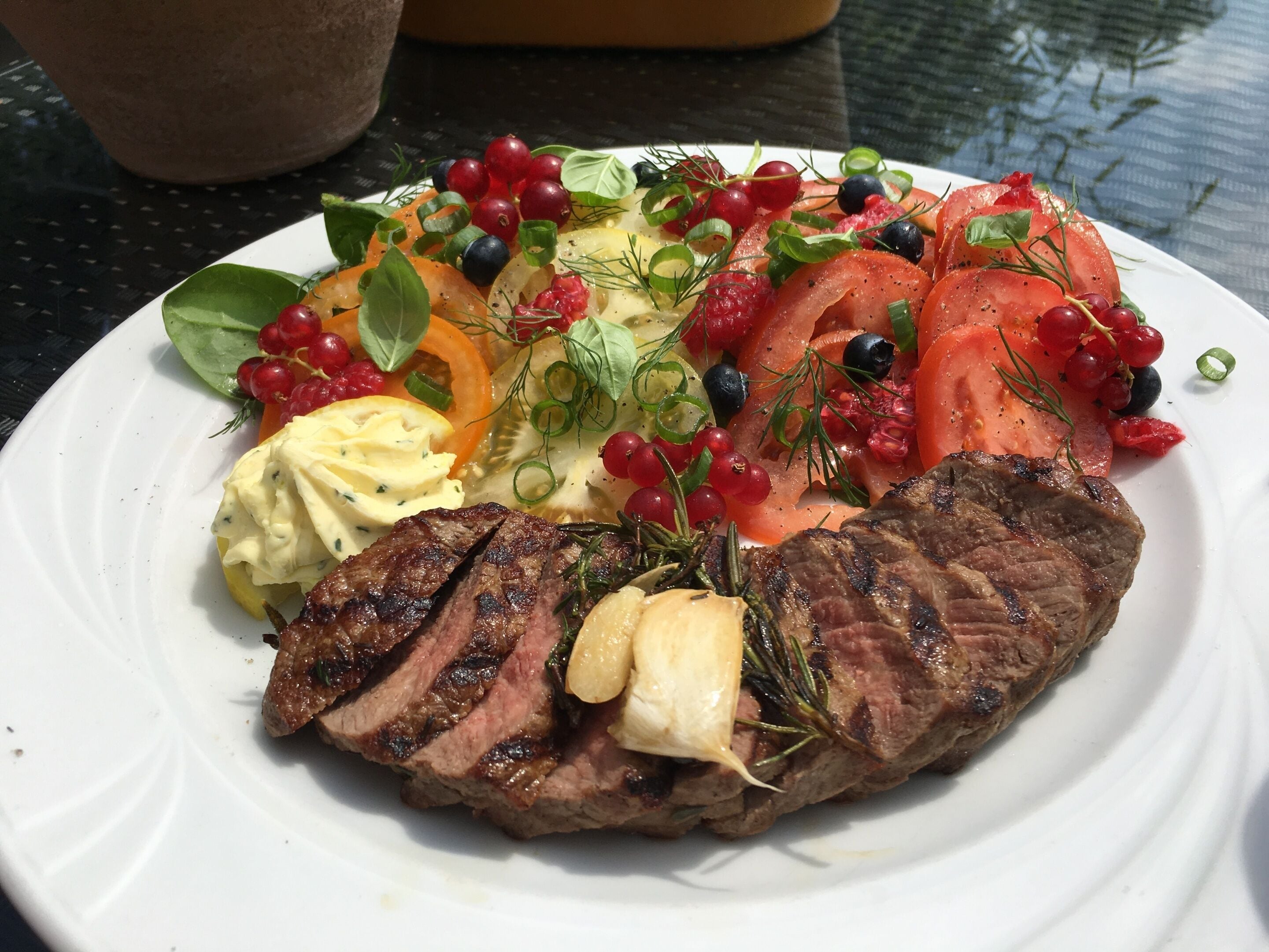 A plate with grilled steak, vegetables, and a creamy sauce.