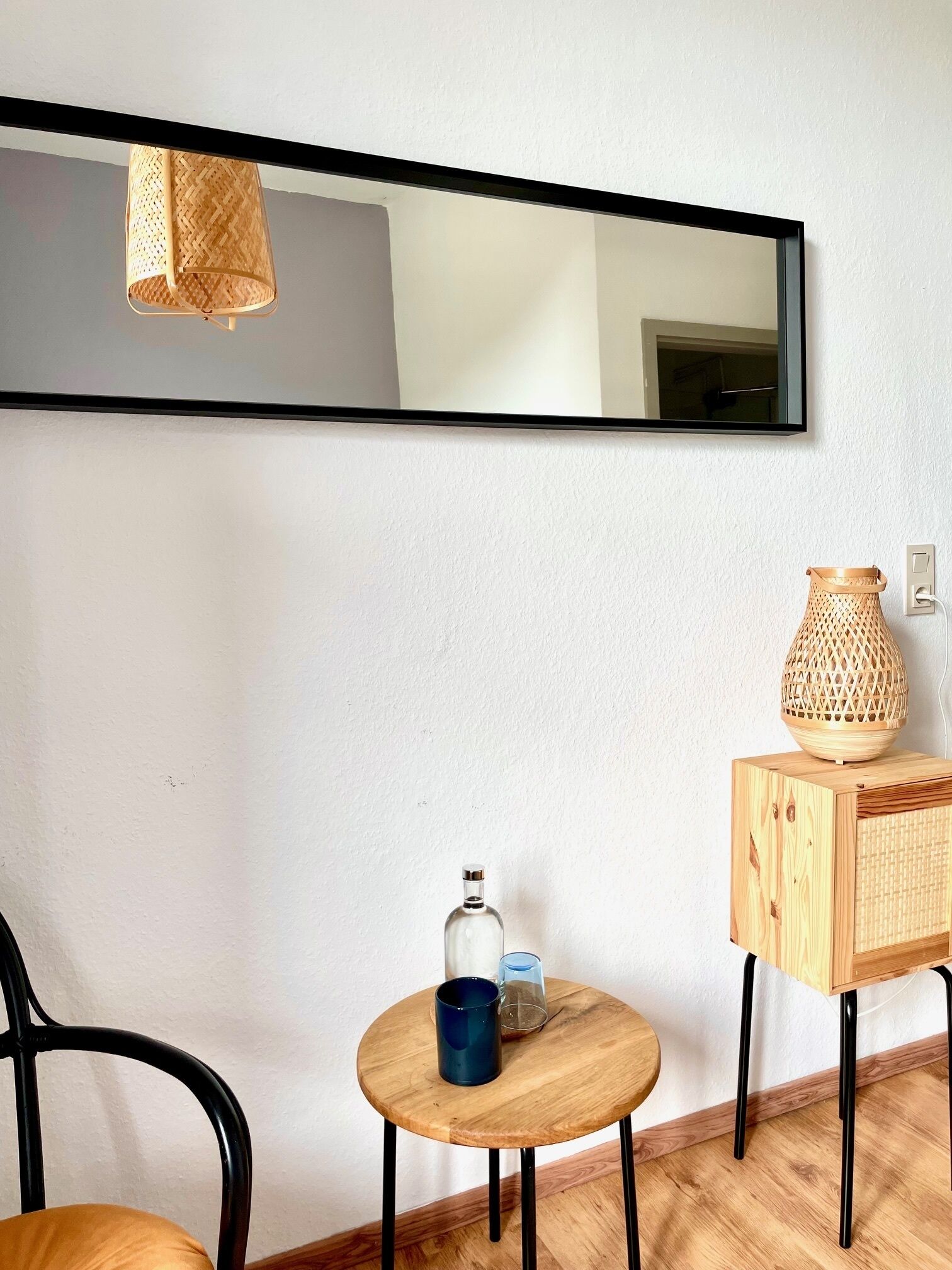 Una stanza con un tavolo rotondo in legno, una sedia, uno specchio e una lampada a parete.