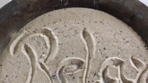A bowl with 'Relax' and a sun symbol in sand. - Hotel Klostermühle (Hann. Muenden)