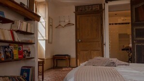 Un dormitorio con una cama, una puerta de madera, una estantería y una lámpara.