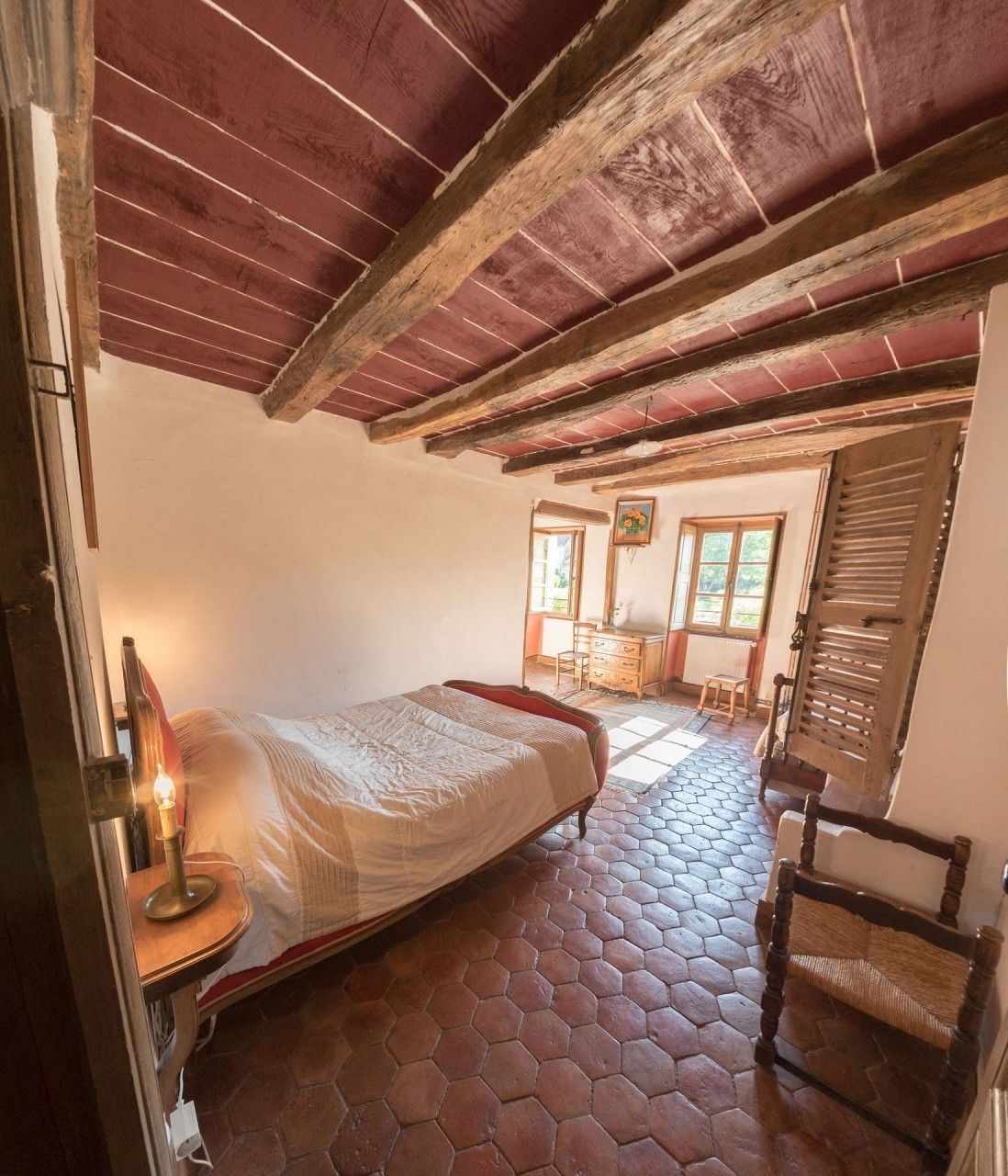 Une pièce comprenant un lit, une chaise en bois, une commode et une fenêtre.