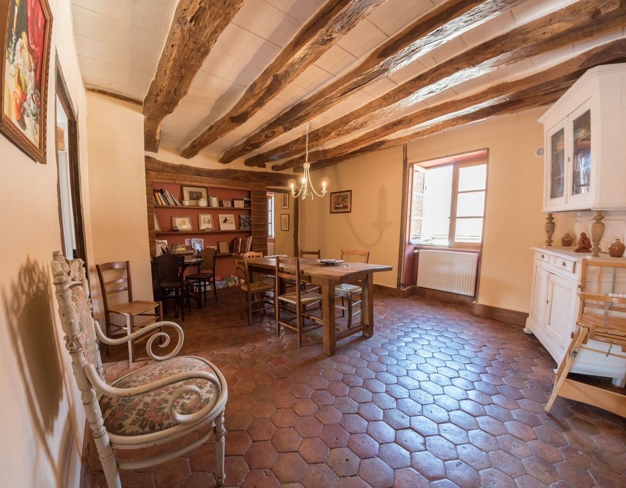 A rustic interior with a hexagonal tiled floor, wooden furniture, and exposed wooden beams on the ceiling.