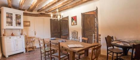 A rustic dining area with a wooden table and chairs, a white cabinet, and a hexagonal tiled floor.