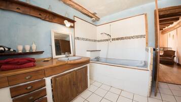 A bathroom with a wooden vanity, a sink, a mirror, a bathtub, and a shower.